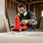 Worker using a professional drywall sander with LED lighting on a ceiling – dust extraction hose attached, illuminated sanding head for precise finishing.